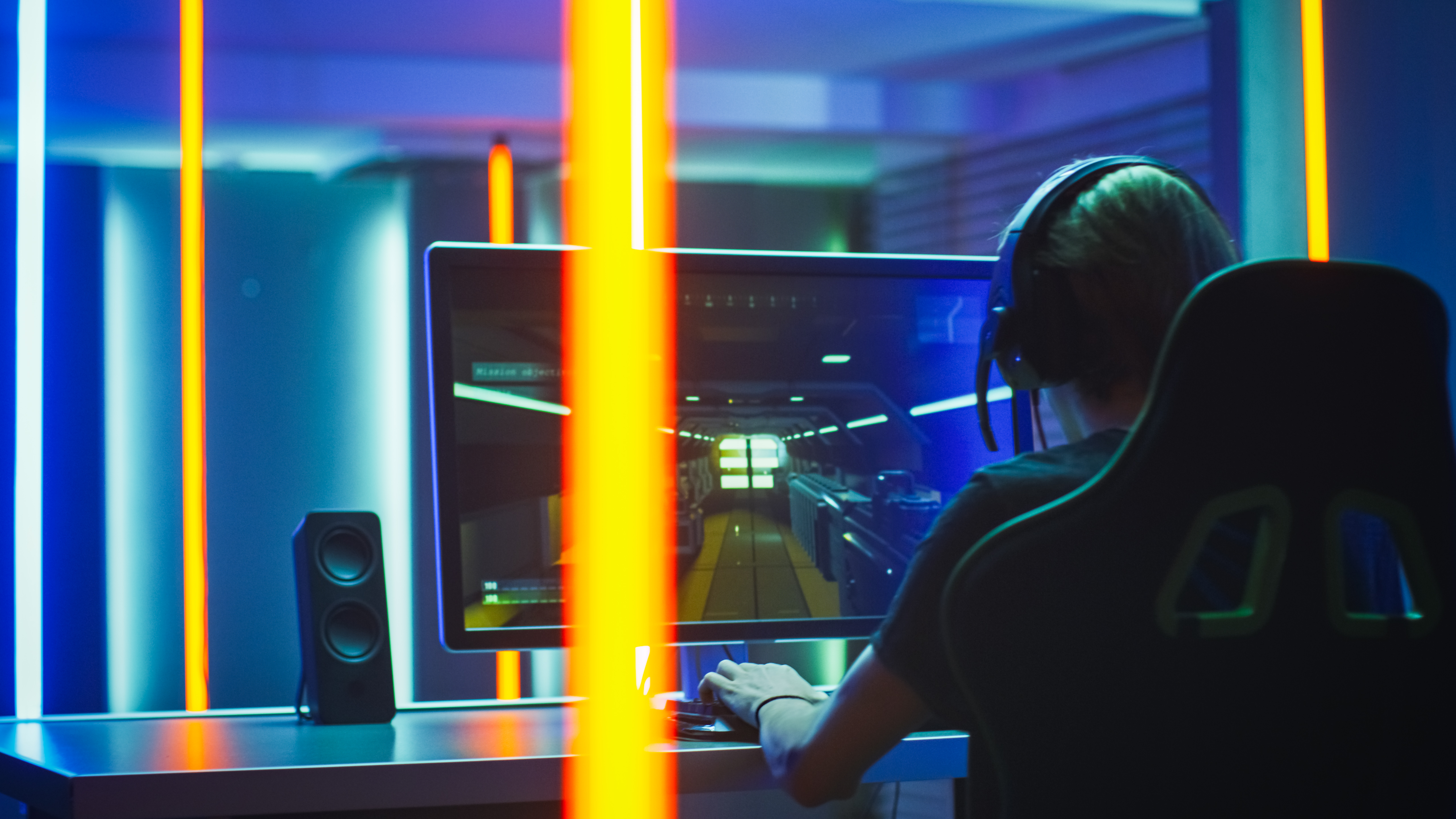 Pro Gamer Plays in the First Person Shooter on His Personal Computer. Talks with Teammates through Headphones. Neon Colored Room. Online eSport Tournament in Action.