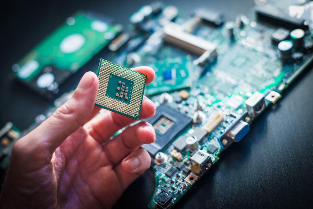 Close up photo of the person's hand holding a computer processor over a motherboard.