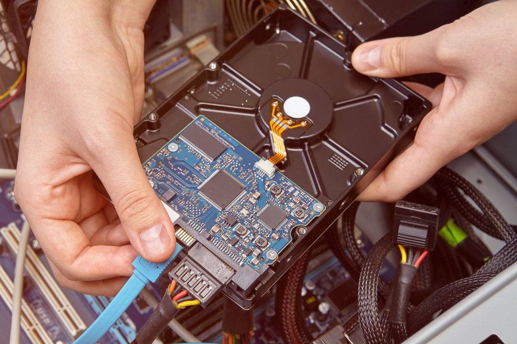 Repairman is connecting the SATA hard drive data cable to the personal computer.