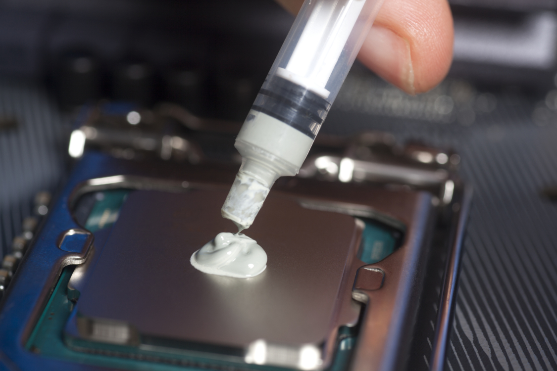 Hand with syringe applying thermal paste on the CPU processor on motherboard Close up